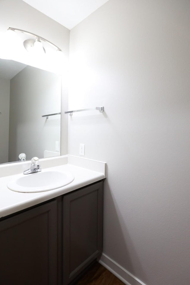 bathroom with vanity, wood finished floors, and baseboards