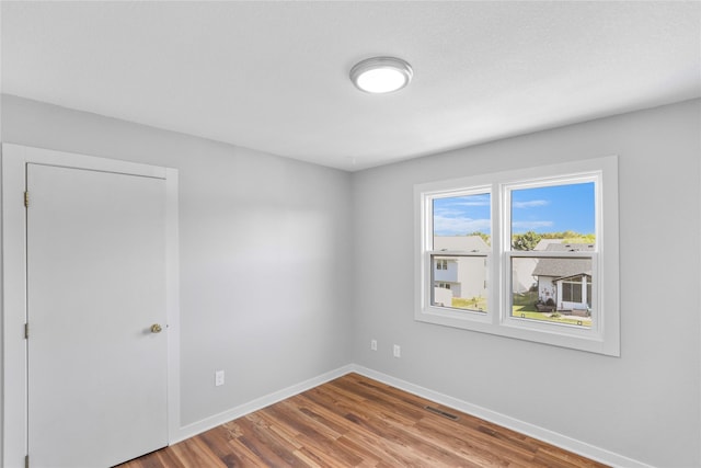 empty room with visible vents, baseboards, and wood finished floors