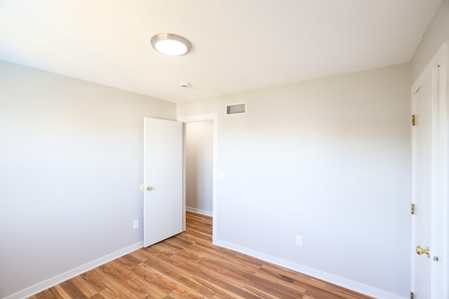 unfurnished room featuring light wood finished floors, visible vents, and baseboards