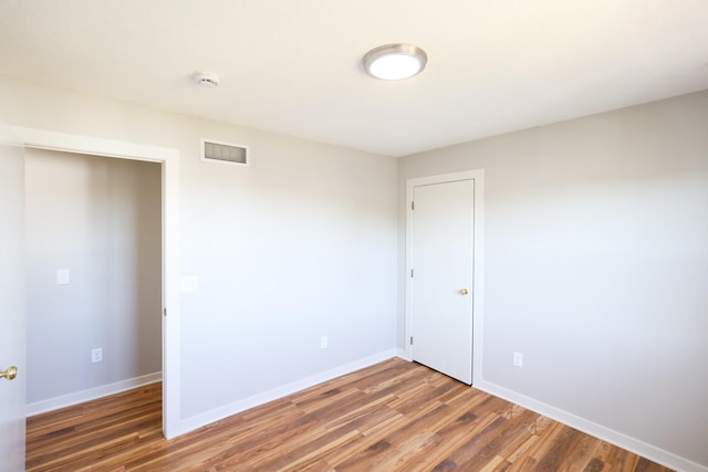 spare room featuring visible vents, baseboards, and wood finished floors