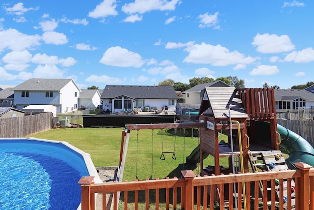 view of pool featuring a fenced in pool, a residential view, a lawn, and a playground