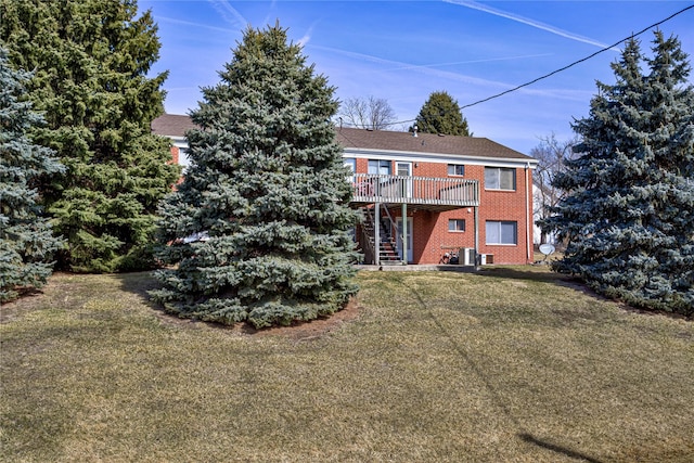 back of house with stairway, a yard, a deck, central air condition unit, and brick siding