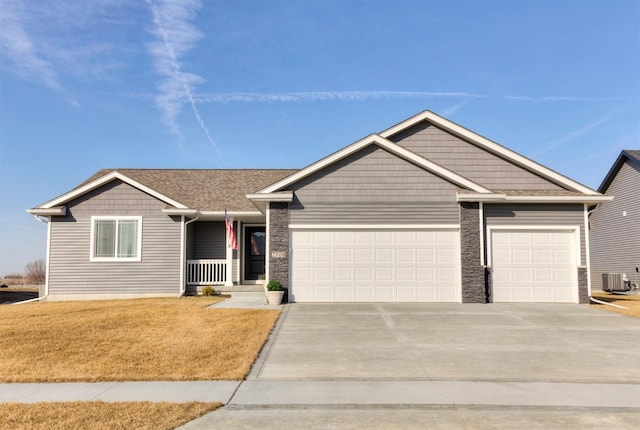 view of front facade featuring central AC, a shingled roof, concrete driveway, a front yard, and an attached garage