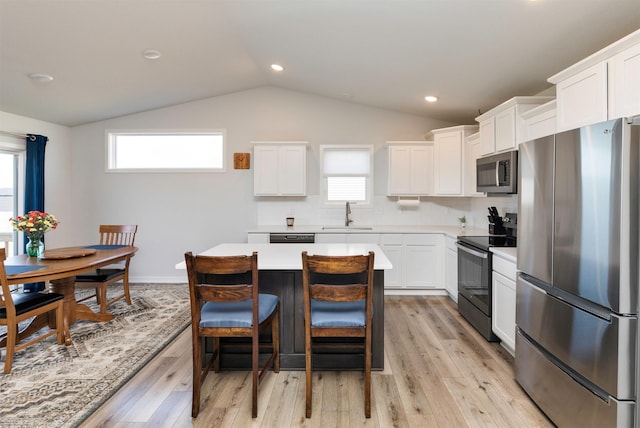 kitchen with a wealth of natural light, a sink, appliances with stainless steel finishes, light countertops, and decorative backsplash