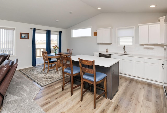 kitchen with vaulted ceiling, plenty of natural light, a breakfast bar, and a sink