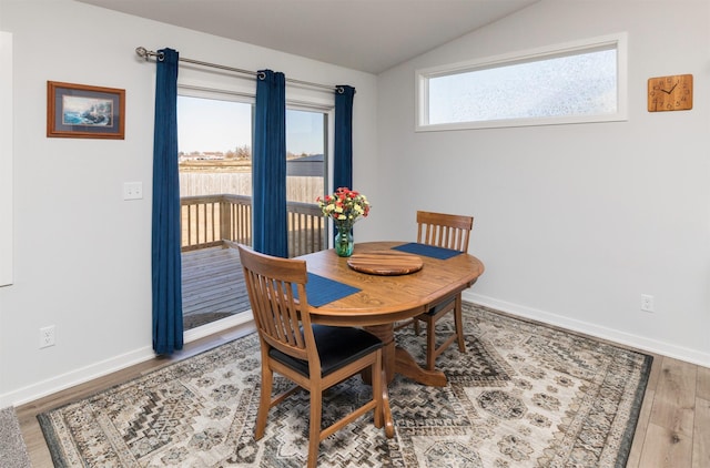 dining room featuring wood finished floors, baseboards, and vaulted ceiling