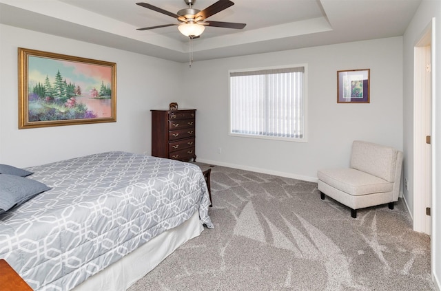 bedroom with a raised ceiling, baseboards, carpet floors, and ceiling fan