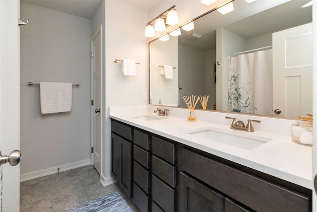 full bath featuring double vanity, baseboards, and a sink