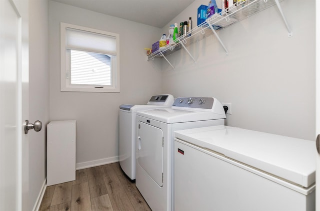 laundry area with laundry area, light wood-style flooring, washing machine and dryer, and baseboards