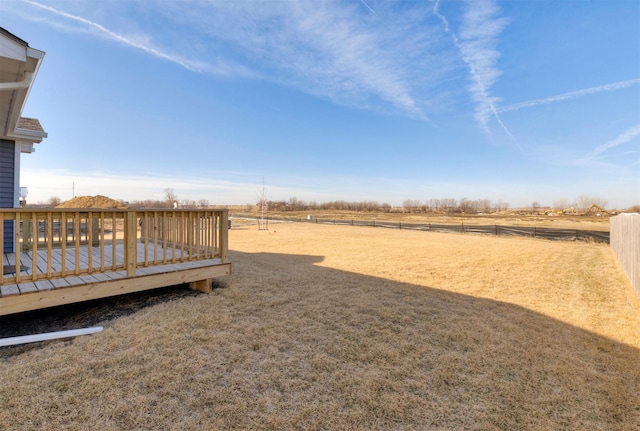 view of yard with a rural view, a deck, and fence