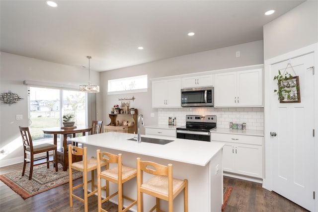 kitchen featuring a sink, tasteful backsplash, stainless steel appliances, light countertops, and dark wood-style flooring