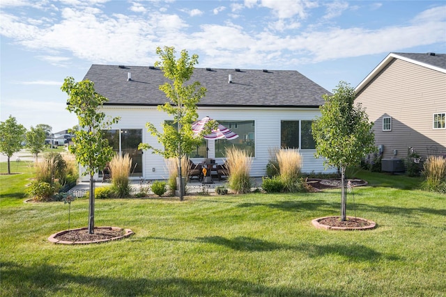 rear view of property with a patio, central air condition unit, a yard, and a shingled roof