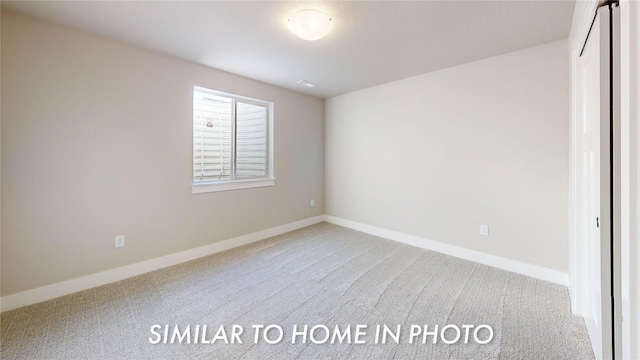 unfurnished room with light colored carpet and baseboards