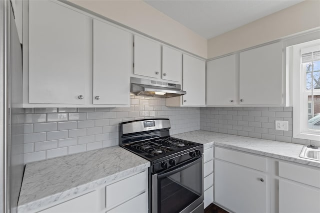 kitchen featuring under cabinet range hood, a sink, white cabinetry, gas stove, and decorative backsplash