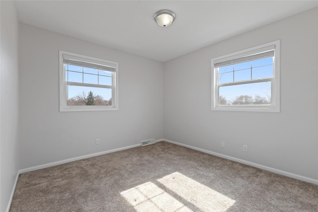 carpeted empty room featuring baseboards, visible vents, and a wealth of natural light