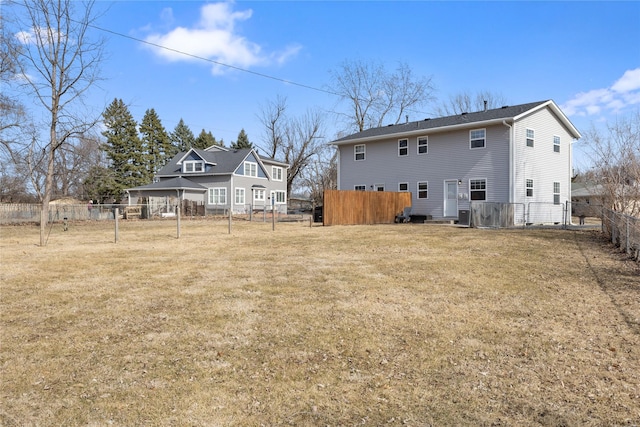 back of property featuring a lawn and fence