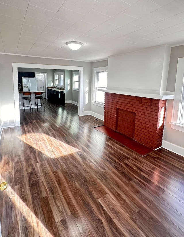 unfurnished living room featuring baseboards, wood finished floors, and a fireplace