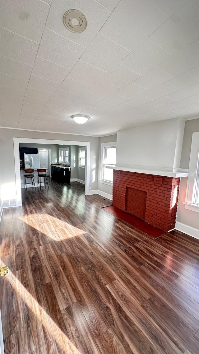 unfurnished living room featuring wood finished floors, a fireplace, and baseboards