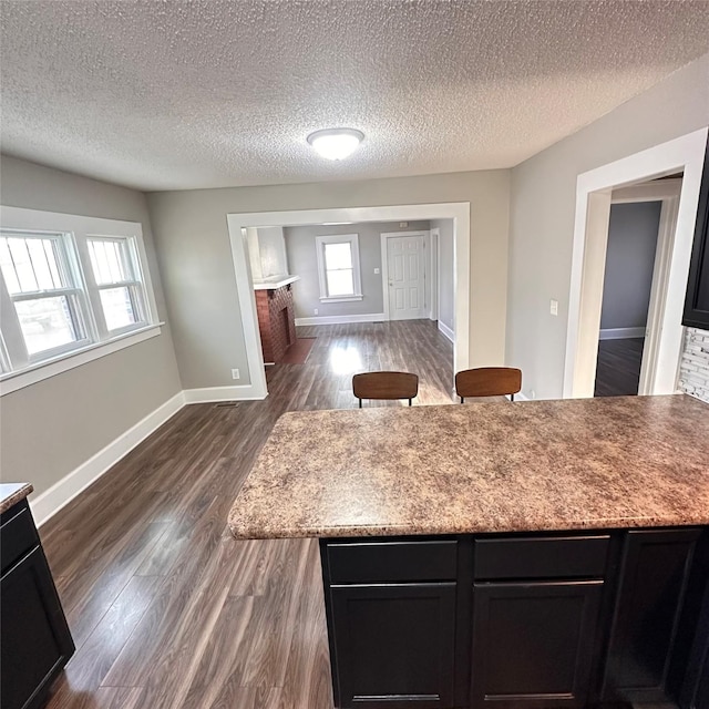 kitchen featuring dark wood finished floors, plenty of natural light, dark cabinetry, and baseboards