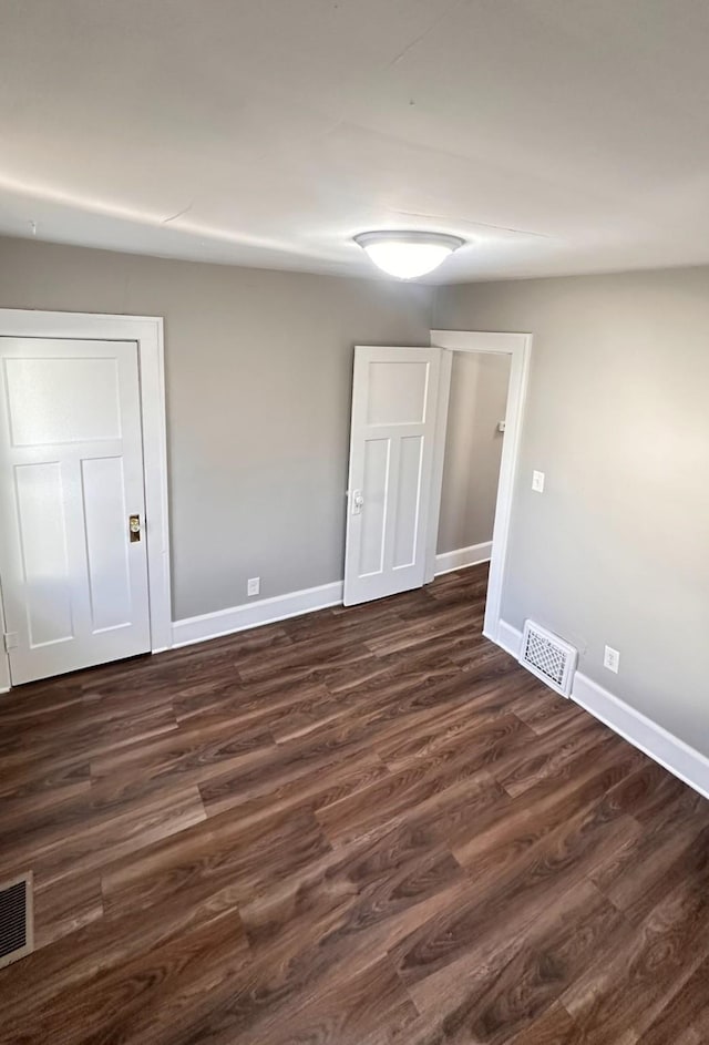 spare room featuring dark wood-style floors, baseboards, and visible vents