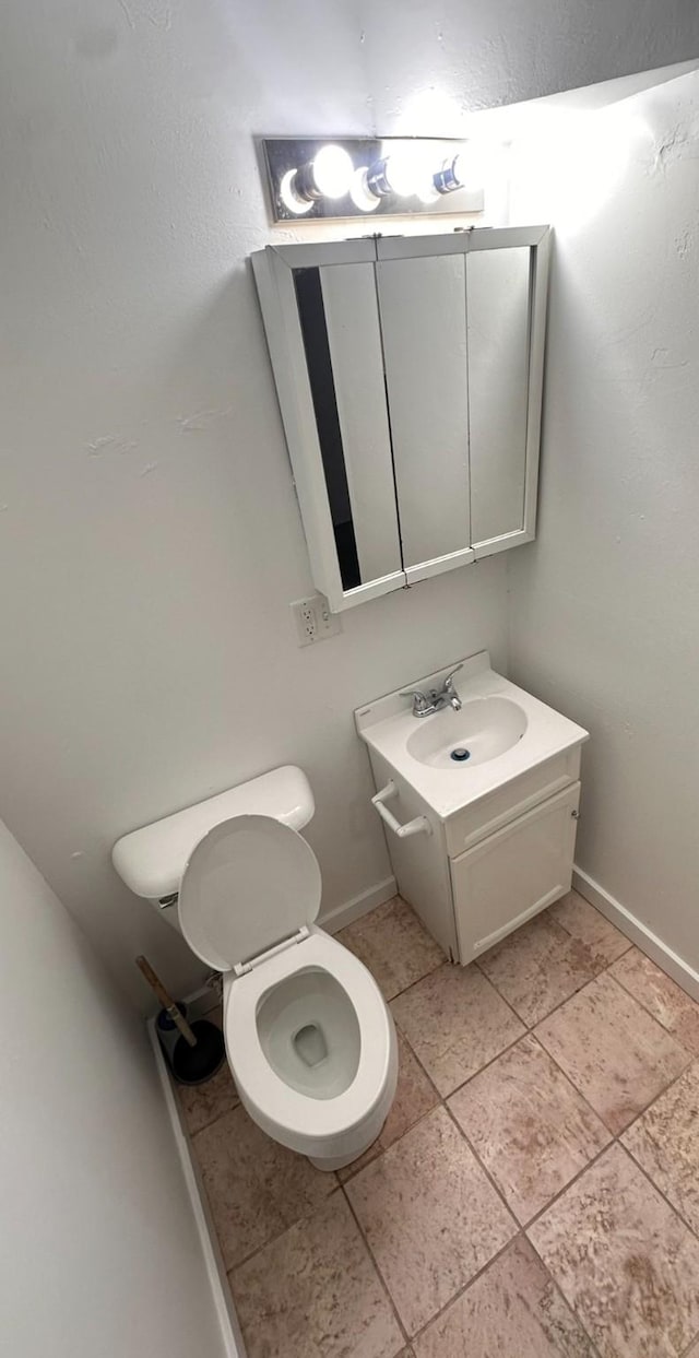 bathroom with toilet, vanity, and baseboards