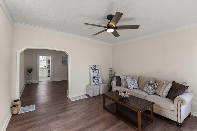 living area with visible vents, ornamental molding, dark wood-style floors, arched walkways, and a textured ceiling