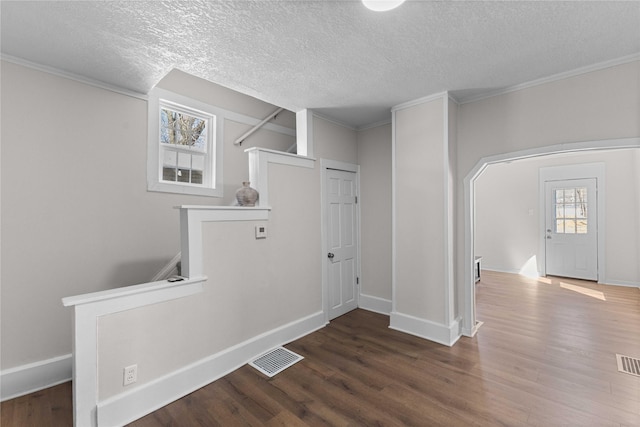 interior space featuring visible vents, crown molding, baseboards, and wood finished floors