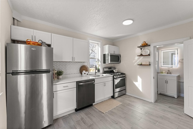 kitchen with a sink, appliances with stainless steel finishes, white cabinets, light countertops, and decorative backsplash