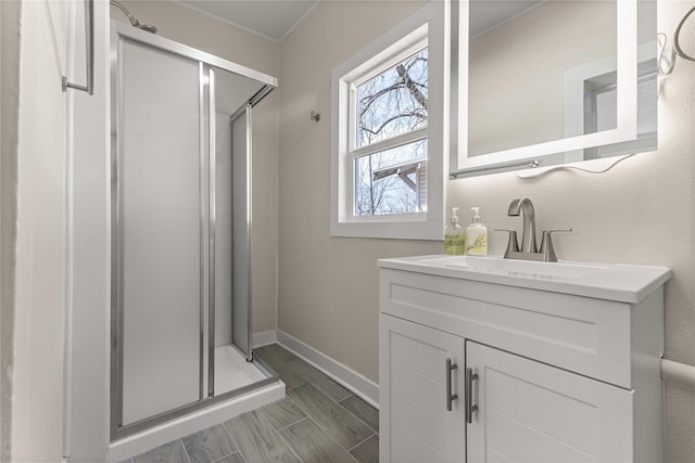 bathroom featuring baseboards, wood tiled floor, a stall shower, and vanity