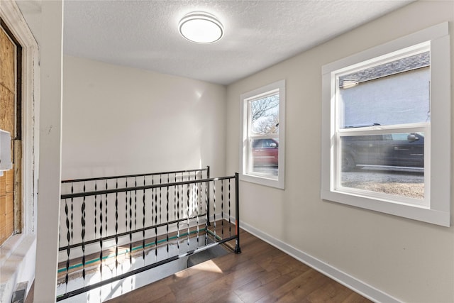 interior space featuring a textured ceiling, baseboards, and wood finished floors