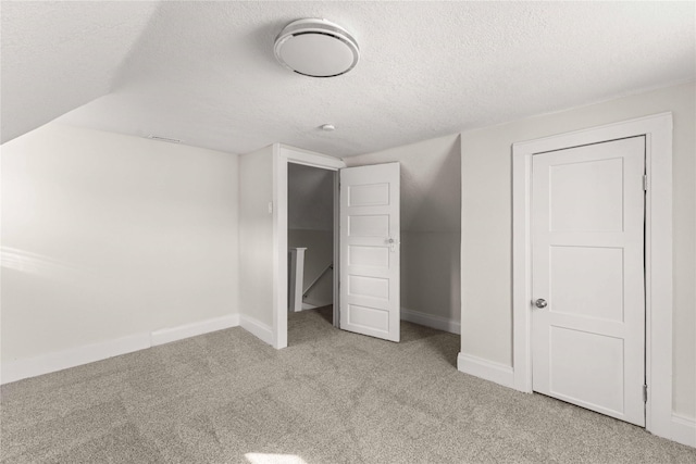 unfurnished bedroom featuring baseboards, a textured ceiling, lofted ceiling, and carpet flooring