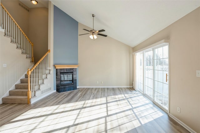 unfurnished living room featuring a fireplace, stairway, wood finished floors, and visible vents