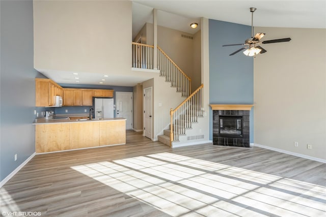 kitchen with light wood-type flooring, a ceiling fan, open floor plan, white appliances, and a peninsula