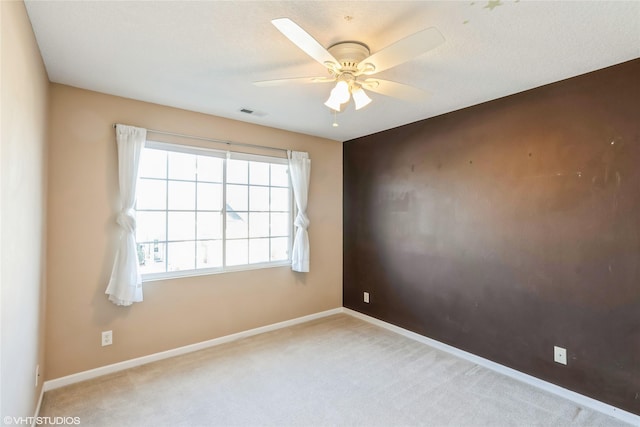 empty room with visible vents, baseboards, carpet, and a ceiling fan