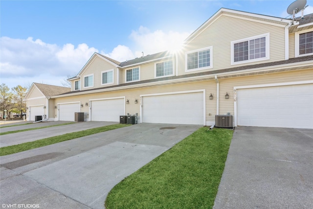 townhome / multi-family property with central AC unit, an attached garage, and concrete driveway