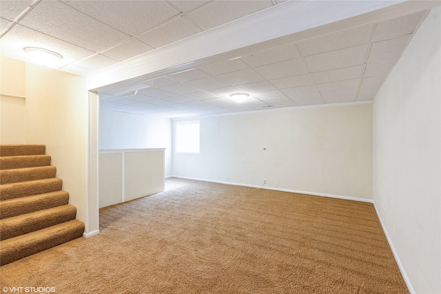 basement featuring stairs, carpet, baseboards, and a paneled ceiling