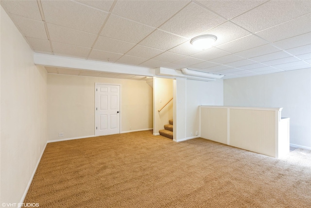 finished basement with baseboards, a paneled ceiling, and carpet