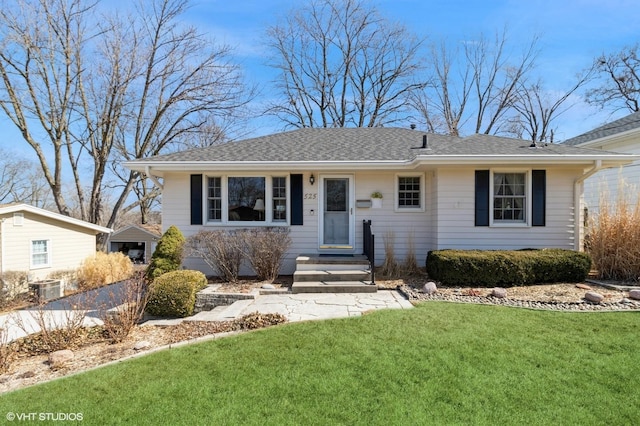 view of front of house featuring central AC unit, a front yard, and roof with shingles