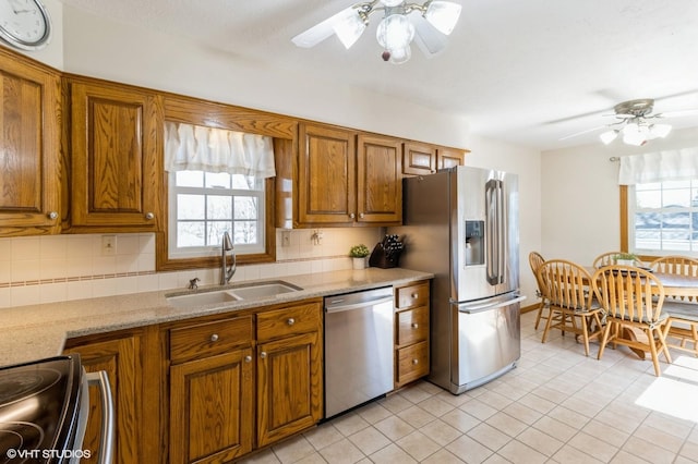 kitchen with a sink, brown cabinets, appliances with stainless steel finishes, and ceiling fan