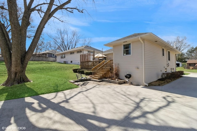 back of house with stairs, a deck, a lawn, and driveway