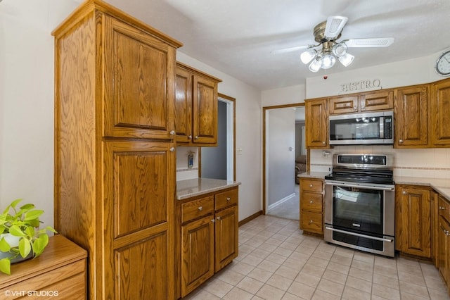 kitchen with light tile patterned floors, ceiling fan, decorative backsplash, stainless steel appliances, and brown cabinets