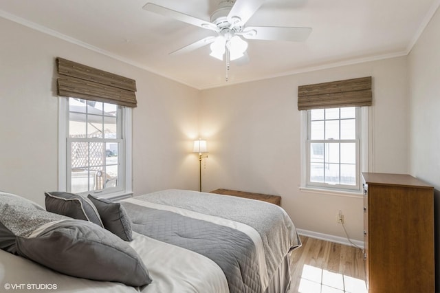 bedroom with crown molding, light wood-style flooring, a ceiling fan, and baseboards