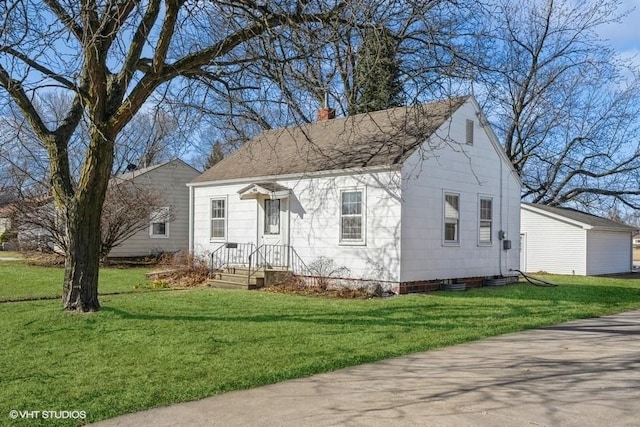 view of front of home with a shingled roof, a front yard, and a chimney