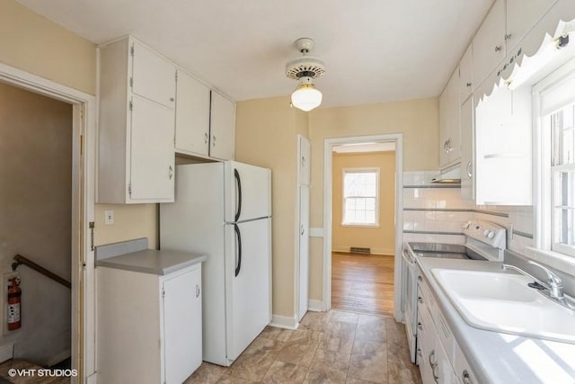 kitchen with white appliances, light countertops, backsplash, and a sink