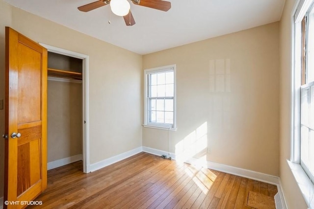 unfurnished bedroom featuring hardwood / wood-style floors, baseboards, a closet, and ceiling fan