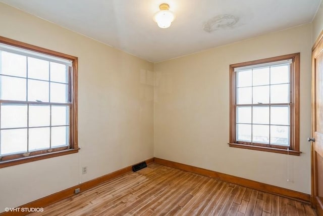 spare room featuring light wood-type flooring and baseboards