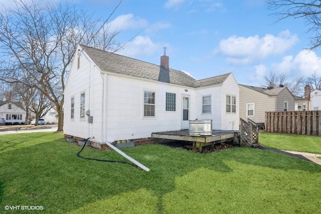 back of property featuring a shingled roof, fence, a wooden deck, a chimney, and a yard