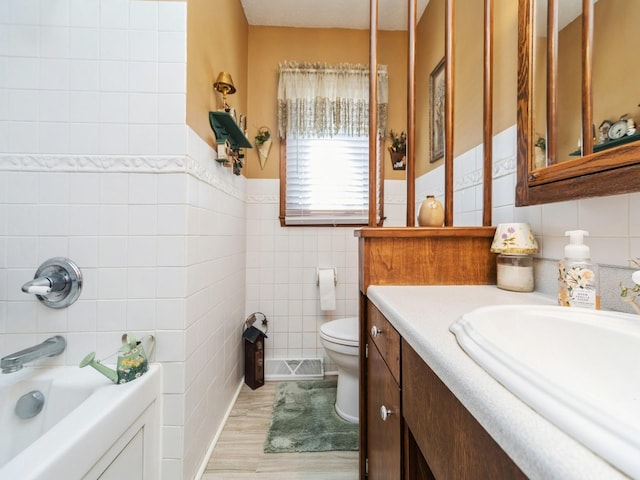 bathroom with vanity, wood finished floors, tile walls, toilet, and a bathtub