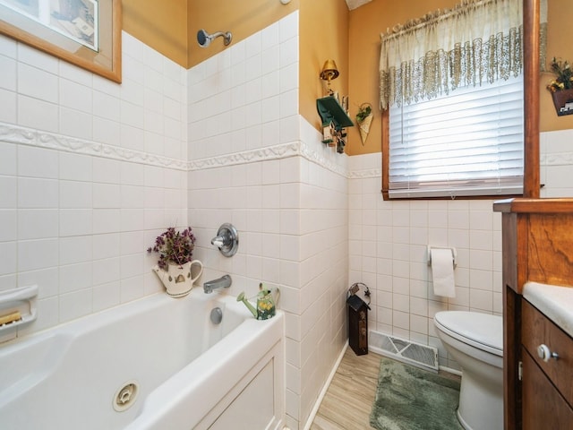 bathroom with visible vents, toilet, a tub, wood finished floors, and tile walls