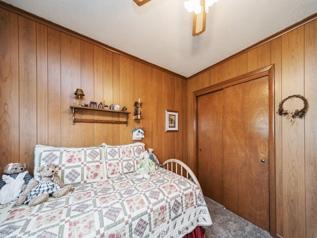 carpeted bedroom featuring a closet, wood walls, and a ceiling fan